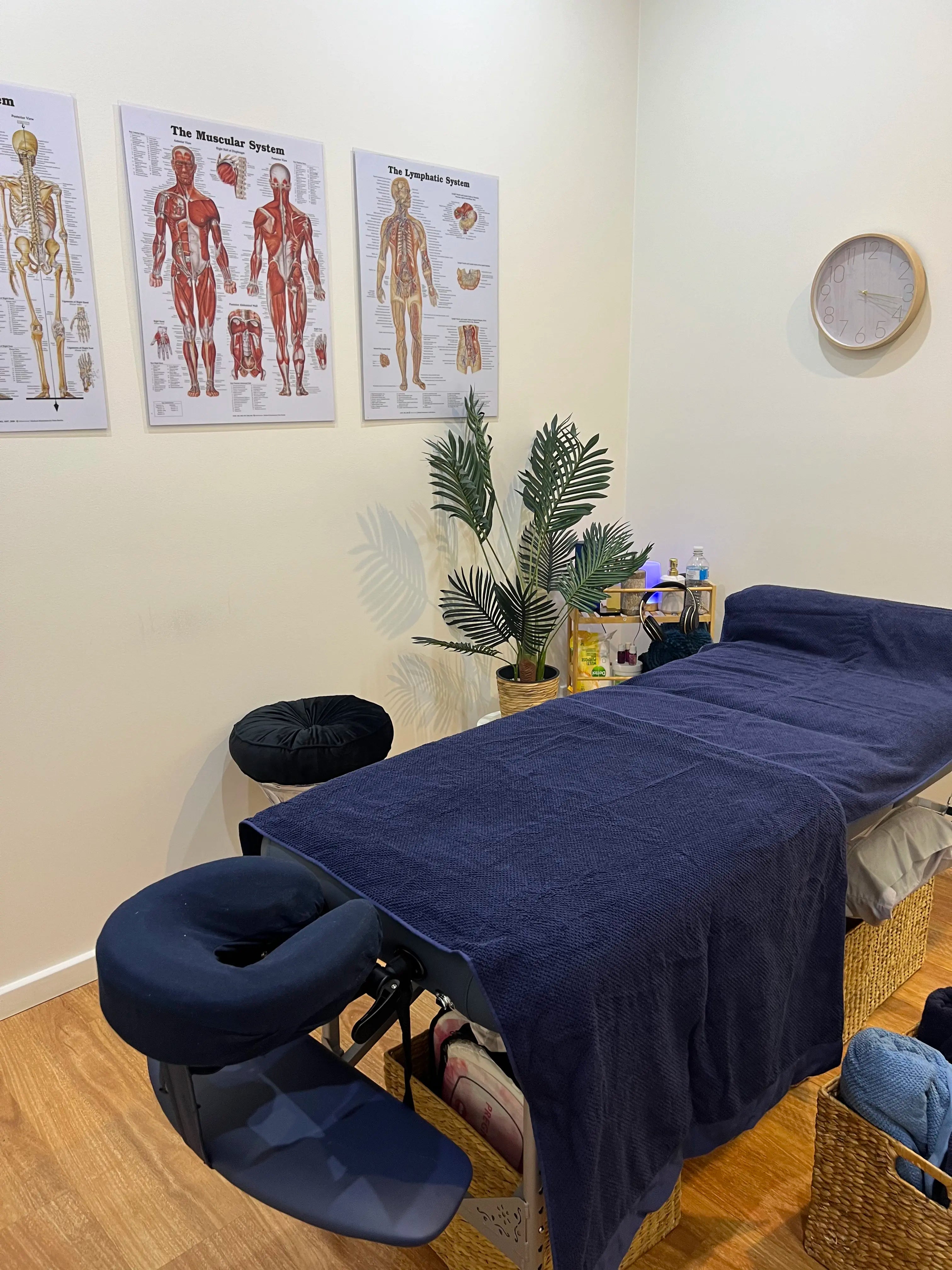 Lymphatic massage setup featuring a prepared table in the foreground and a shelf with essential oils and towels in the background.