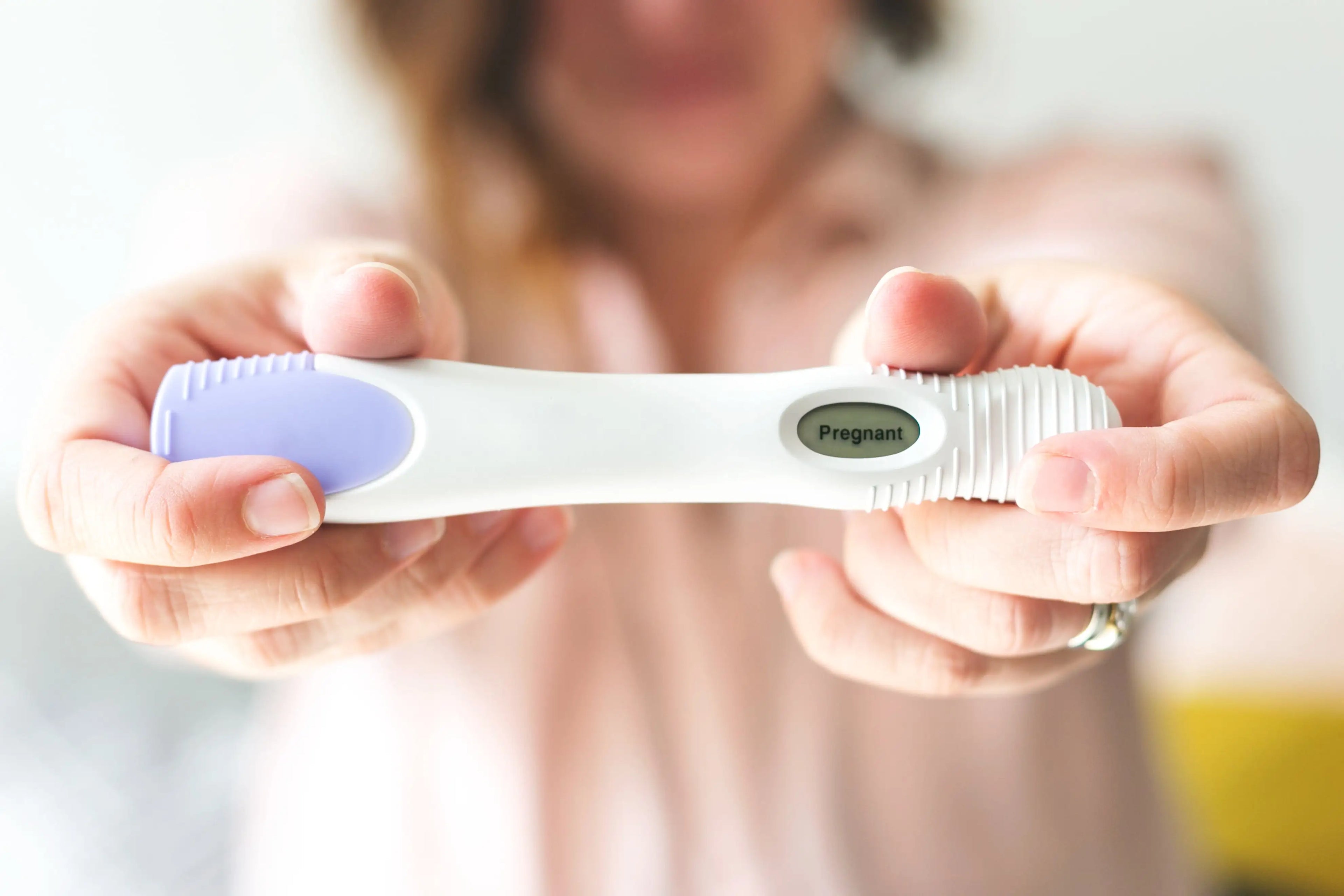 Woman holding a positive pregnancy test.